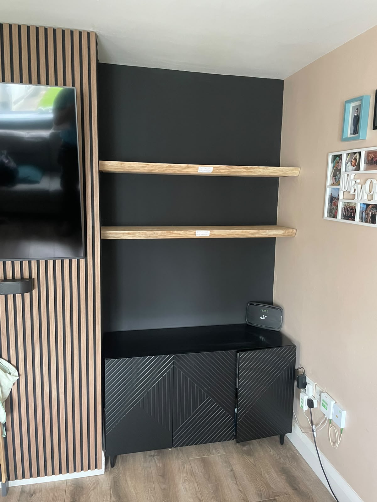 Floating oak shelves above black built-in cabinet by Stonevale Construction